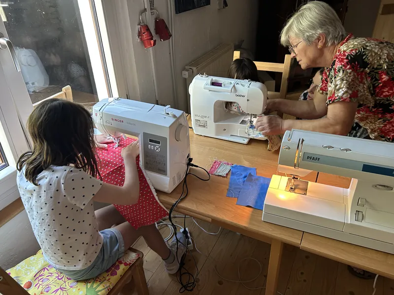 Kinder nähen an Nähmaschinen, Dagmar hilft an einer Maschine